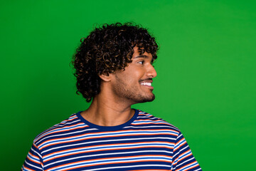 Profile side photo of cheerful nice man wear trendy striped clothes look empty space isolated on green color background