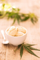 A hemp leaf is lying on a mock-up jars of ice cream on a table