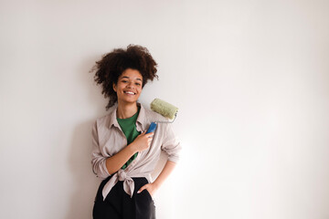 Funny girl of mixed race with roller for painting walls