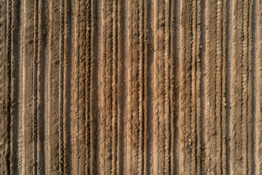 A top-down view of a freshly plowed field, with rows of soil creating a textured pattern.