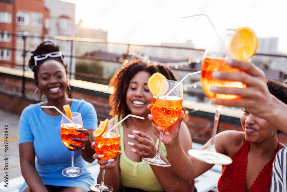 Wall mural company of four cheerful friends are enjoying tasty cocktails. roof party