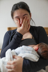 Young mother comforting her baby while holding back tears, illustrating the emotional journey and...