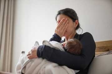 Mother breastfeeding her newborn baby while showing signs of exhaustion, highlighting the challenges and dedication involved in parenting