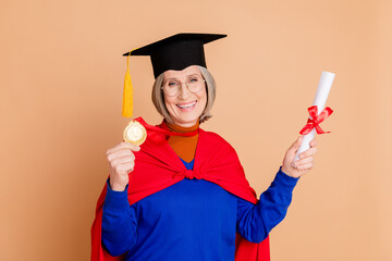 Photo portrait of lovely pensioner lady show diploma golden medal dressed stylish blue garment isolated on beige color background