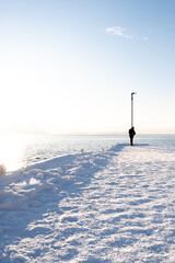 Vertical of a person walking on a snow-covered path in Tjuvholmen, Oslo Norway