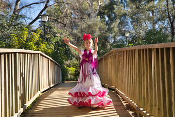 A girl dancing flamenco, playing with soap bubbles, in typical flamenco dress, on a wooden bridge. Concept dance, flamenco, typical Spanish, Seville, Spain.