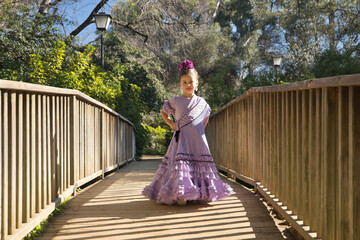 Girl dancing flamenco, posing looking at the camera, in typical flamenco dress, on a wooden bridge. Concept dance, flamenco, typical Spanish, Seville, Spain.