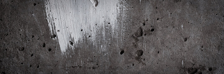 Texture of old concrete wall. Rough grey surface of concrete with a white smear of paint. Wide...