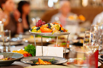 a large served festive table with appetizers. Fruit dish stand in the center of the table.