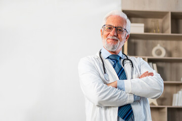 Mature senior male doctor in glasses medical uniform smiling looking at camera in hospital or...