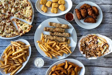 Close-up of an assortment of prepared dishes with pizza and French fries on a wooden table