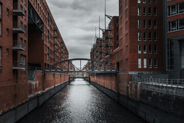 Naklejka premium a narrow canal running through a city near tall buildings and a bridge, Hamburg, Germany