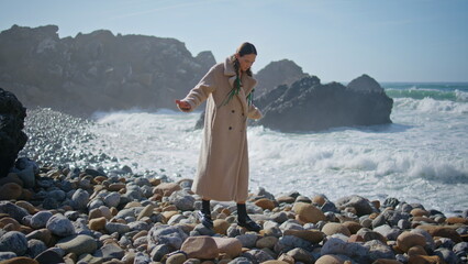 Girl walking beach stones in sunlight. Thoughtful traveler balancing rocky beach - Powered by Adobe