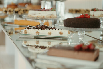 several cakes and pastries sitting on glass dishes, along with a candle on the