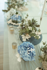 an elegant table is set with blue flowers and greenery