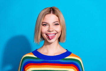 Portrait of pretty young girl show tongue out wear striped pullover isolated on blue color...