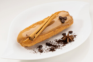 Delicious coffee-flavored eclair dessert decorated with coffee beans and cinnamon stick