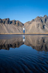 Vertical of a young Caucasian woman posing against a lake on a sunny day