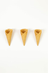 Top view of three ice cream waffle cones on white background. Summer wallpaper, flat lay, copy space.