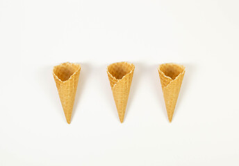 Top view of three ice cream waffle cones on white background. Summer wallpaper, flat lay, copy space.