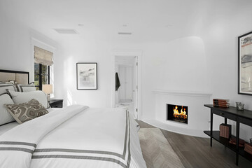 Sophisticated and stylish bedroom with a stunning white color palette and central fireplace