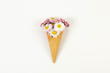 Top view of daisy flowers bouquet on white background. Creative ice cream waffle cone. Spring and...