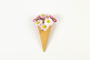 Top view of daisy flowers bouquet on white background. Creative ice cream waffle cone. Spring and summer wallpaper, flat lay, copy space.