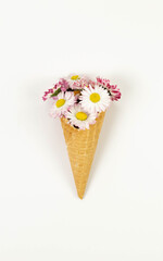 Top view of daisy flowers bouquet on white background. Creative ice cream waffle cone. Spring and summer wallpaper, flat lay, copy space.