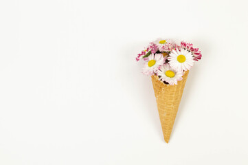 Top view of daisy flowers bouquet on white background. Creative ice cream waffle cone. Spring and...