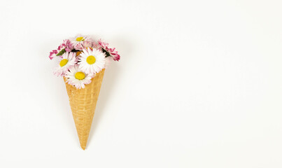 Top view of daisy flowers bouquet on white background. Creative ice cream waffle cone. Spring and summer wallpaper, flat lay, copy space.