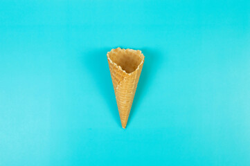 Top view of ice cream waffle cone on blue background. Summer wallpaper, flat lay, copy space.