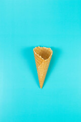 Top view of ice cream waffle cone on blue background. Summer wallpaper, flat lay, copy space.