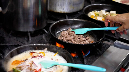 Person cooking and preparing traditional Thai cuisine in pans.