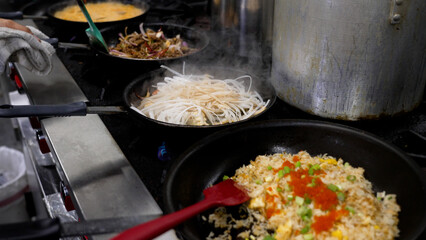 Person cooking and preparing traditional Thai cuisine in pans.