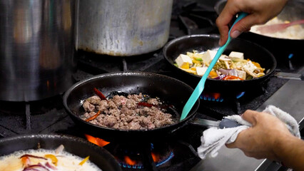 Person cooking and preparing traditional Thai cuisine in pans.