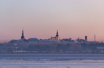 Obraz premium Scenic view of the skyline of Tallinn city skyline over the sea bay at sunset