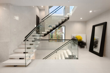 Modern home interior featuring a set of stairs with white carpeting and glass railings