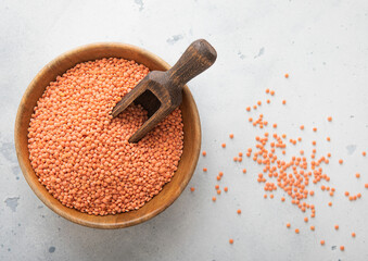 Dry raw orange lentils seeds in wooden bowl with scoop on light table.Macro.