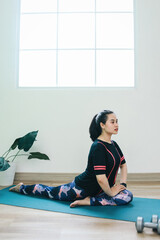 Young Asian woman practicing yoga at home