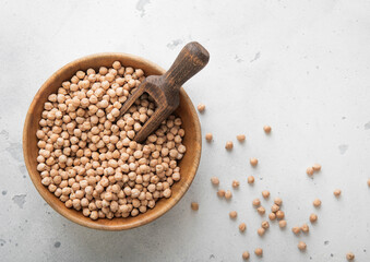 Wooden bowl with scoop of dry raw chickpea organic seeds on light table.Macro.