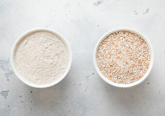 Bowls plates with dry raw melted buckwheat seeds and flour powder on kitchen table.Macro.