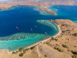 A serene view of boats anchored near a narrow strip of beach dividing turquoise waters