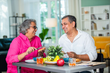 senior Indian asian mid age couple having fun during a breakfast at home.