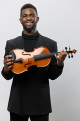 Happy African American man smiling and holding violin in front of face on white background Musician...