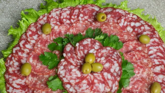 Beautiful serving of salami with garnished with olives and herbs, cold cuts