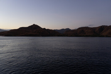 Tranquil dusk over a serene lake with gentle hills in the background