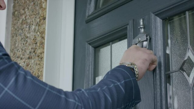 Closeup footage of adult male hand using the door knocker to knock the door