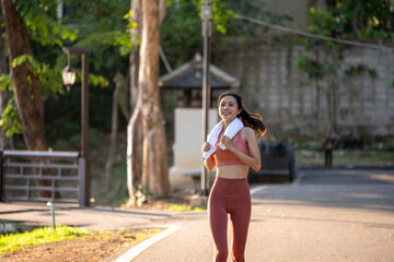 A woman is running in a park with a towel in her hand