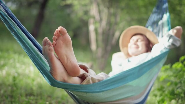 Close-up of female feet. A young Caucasian woman chilling in a hammock in the spring garden.