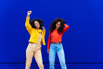 Young happy women having fun outdoor. Teenagers listening to music with smartphone and headphones...